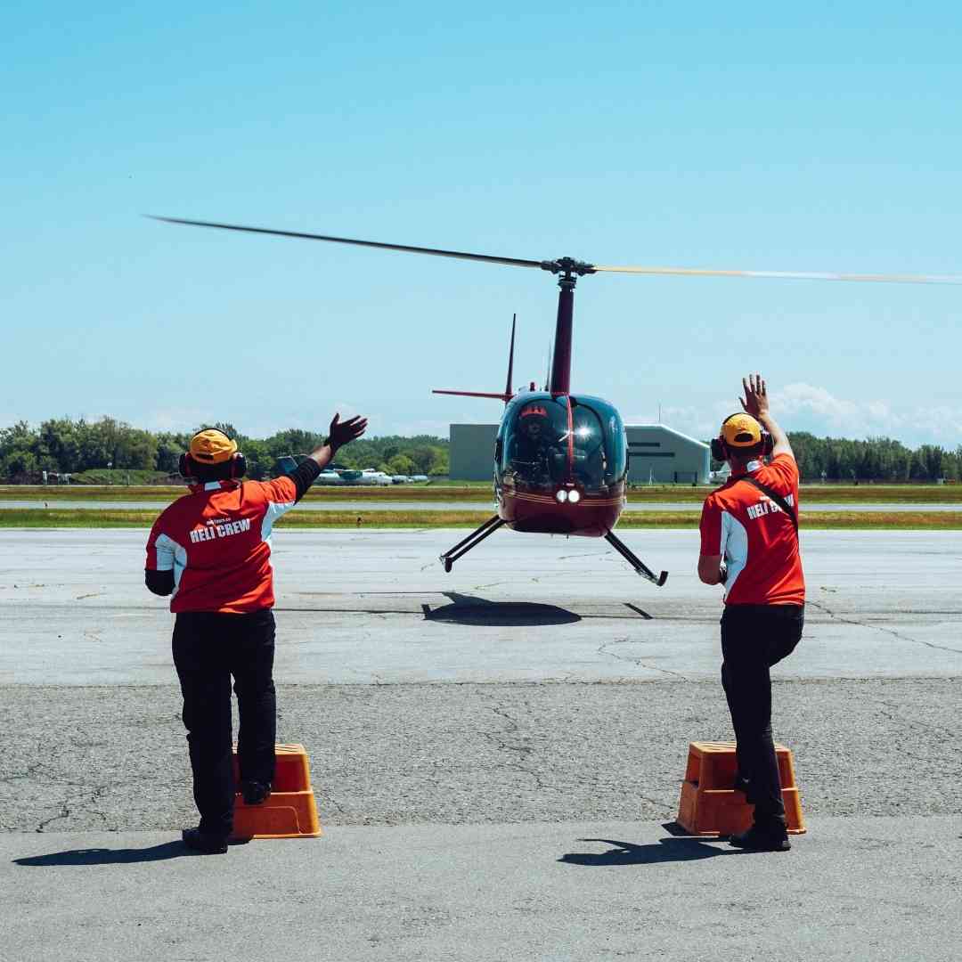 A helicopter taking off, with ground crew waving goodbye